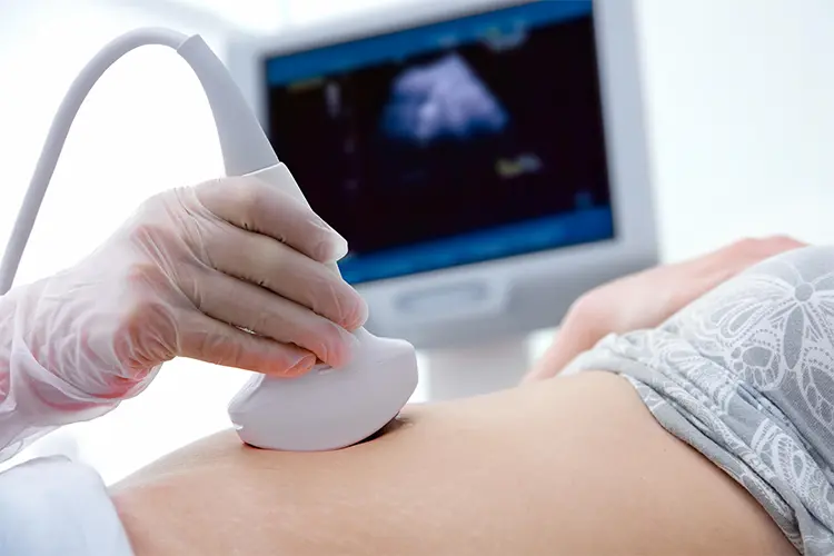 Especialista realizando una ecografía en la barriga de una mujer, con la imagen reflejada en la pantalla, en Lima
